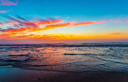 Sea landscape on sunset or sunrise with ocean waves and orange colorful clouds in sky. Concept of vacation on beach, free time, travel, summer, disconnecting from routine and relaxing.の写真素材