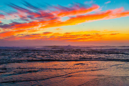 Sea landscape on sunset or sunrise with ocean waves and orange colorful clouds in sky. Concept of vacation on beach, free time, travel, summer, disconnecting from routine and relaxing.の写真素材