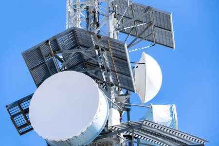 Telecommunication tower with television (TV), satellite and 5G antennas with blue sky. Arrival of 5G mobile telephony and problems of electromagnetic radiation and cancer of electromagnetic waves.の写真素材