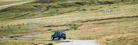 Off-road vehicle driving on a mountainous trail in a mountainous landscape. Routes and excursions in 4x4 through the mountains in summer. Concept of exploring and live adventures traveling in nature.の写真素材