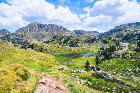 Mountainous landscape with beautiful green mountains and a lake on a sunny day. Concept of mountain trip and summer vacations. Circo Saboredo, Aran Valley, Pyrenees, Catalonia, Spain.の写真素材