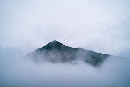 Misty foggy mountain landscape with copyspace in gloomy morning atmosphere. Dark tone, bad weather...