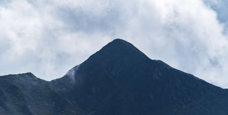 Panoramic view of a peak of a high mountain on a cloudy day. Mountain range. Mountaineering and nature concept.の写真素材