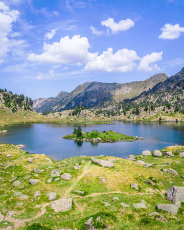 Beautiful Mountain lake surrounded by mountains with green grass on a lovely sunny summer day. Concept of mountain trip and summer vacations. Circo Saboredo, Aran Valley-Pyrenees, Catalonia, Spain.の写真素材