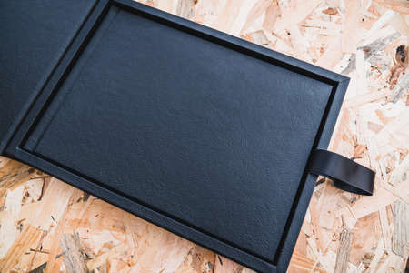 Black leather photo album on a table with vintage wood background. Wedding or family photo book memories with a nice leather box. Family value memory.の写真素材