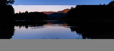 Panoramic landscape of beautiful sunrise or sunset on an alpine lake in the Pyrenees, Catalonia, Spain. Concept of vacations, summer, relaxation and disconnection in nature. Wilderness.の写真素材