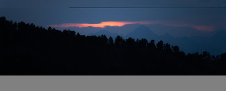 Panoramic mountains layers during sunset or sunrise. Landscape with dark misty silhouettes of alpine mountains and fir trees forest in Pyrenees.の写真素材
