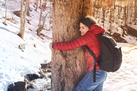 Thoughtful Girl Hugging Tree Trunk at the winter Park with Eyes Closed. Love nature concept.の写真素材