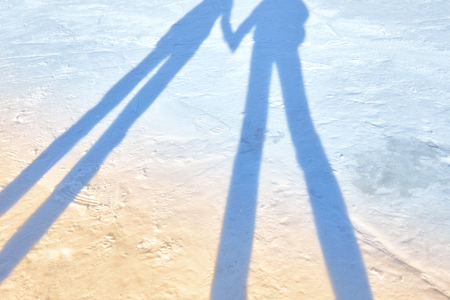 shadows of two people on the fresh snow holding handsの写真素材