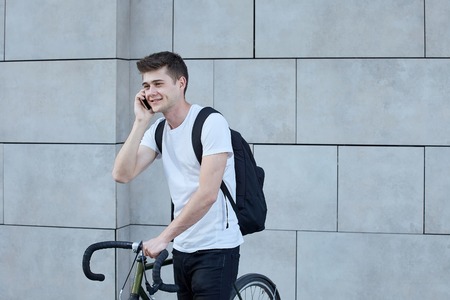 Handsome hipster man posing with bicycle in the city.の写真素材