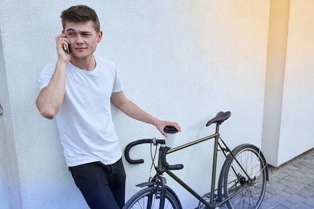 Handsome hipster man posing with bicycle in the city.の写真素材