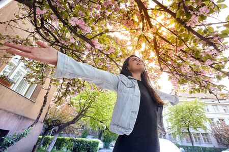 Young girl with arms wide open and enjoying in sunshine standing outdoor in sun light on the...