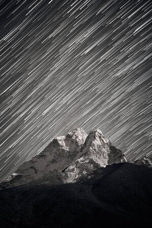 Stars falling above Ama Dablam mountain peak lit up by a bright moonlight. Stars trails above...