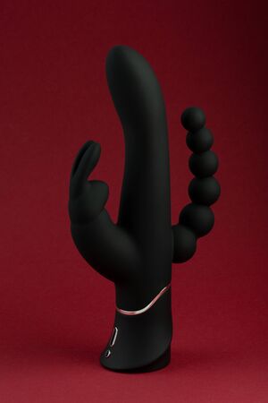 Black sex toy for adult dildo happy rabbit vibrator isolated on red background. Vaginal dildo with vibration. Space for text. Image for the sex shopの写真素材