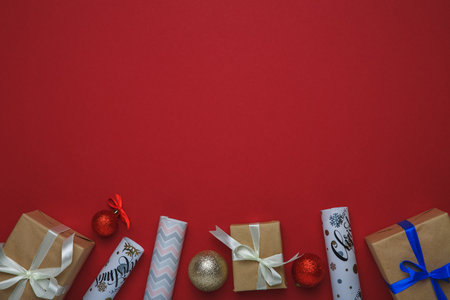 Christmas and New Year background with fir tree and decor. Top view with copy space. Present. Gift boxes, decorations Christmas balls and wrapping paper on red background.の写真素材