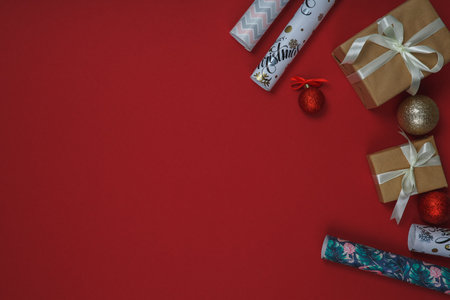 Christmas and New Year background with fir tree and decor. Top view with copy space. Present. Gift boxes, decorations Christmas balls and wrapping paper on red background.の写真素材