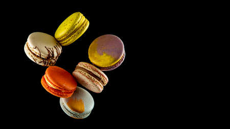 Set of flying colorful macaroons isolated on black background Macaron or macaroon cakes hang in the air. Sweet and colorful dessert Copy Space Colored levitates French cookiesの写真素材