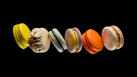 Set of flying colorful macaroons isolated on black background Macaron or macaroon cakes hang in the air. Sweet and colorful dessert Copy Space Colored levitates French cookiesの写真素材