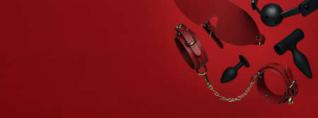 Set of erotic toys for BDSM on a red background. The game of sexual slavery with a whip, gag and leather blindfold. Intimate sex games Erotic toy for fun Sex gadget and masturbation device. Sex Shopの写真素材