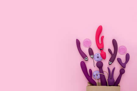 A paper shopping bag filled pink Purple silicone sex toys on a white background. Erotic toy for fun. Sex gadget and masturbation device. View from above. Place for text. Flat lay. Sex shop concept.の写真素材