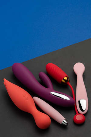 Multi-colored sex toys on a black and blue background. Erotic pleasure toy. Sex gadget and masturbation device. Top view. Place for text. Flat lay. Sex shop concept wiht dildo, vibratorの写真素材
