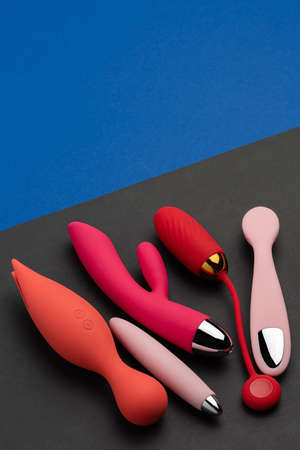 Multi-colored sex toys on a black and blue background. Erotic pleasure toy. Sex gadget and masturbation device. Top view. Place for text. Flat lay. Sex shop concept wiht dildo, vibratorの写真素材