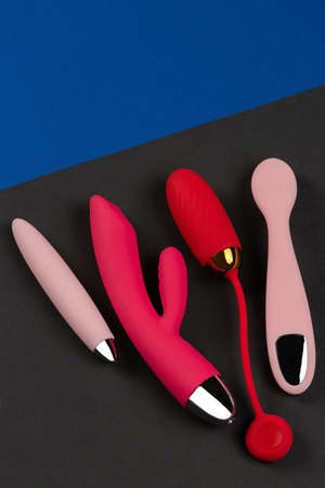 Multi-colored sex toys on a black and blue background. Erotic pleasure toy. Sex gadget and masturbation device. Top view. Place for text. Flat lay. Sex shop concept wiht dildo, vibratorの写真素材