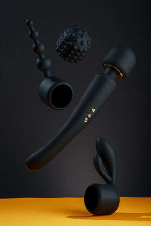 Black silicone sex toys flying in the air on a black background Sex gadget and masturbation device Sex shop concept Vaginal and anal balls, clitoral dildo rabbit Sexual Clitoris Massagerの写真素材