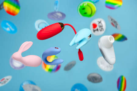 Bright colorful concept for sex shop. Vaginal balls, dildo for the clitoris, We-Vibe and Womanizer on a background of rain out of condoms. Festive image of sex toys, gadgets, masturbation device.の写真素材