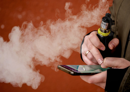 a man smokes an electronic cigarette. VAPE lets smokeの写真素材