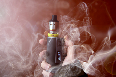 electronic cigarette in smoke on brown background