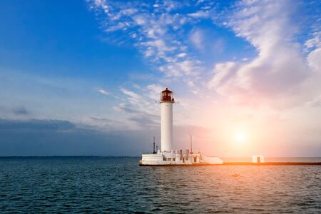 lighthouse in the sea at sunsetの写真素材