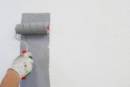 hand with paint roller in hand, painting a wall