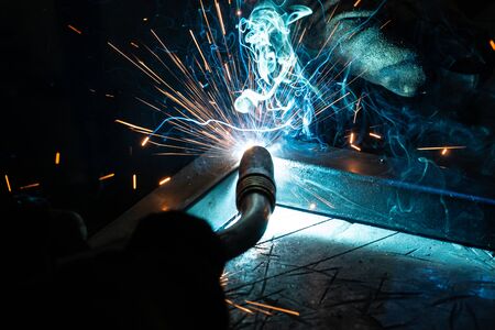 The welder cooks the frame. The welder cooks the metal. The welder cooks metal structures. Welding works. Sparks, molten metalの写真素材