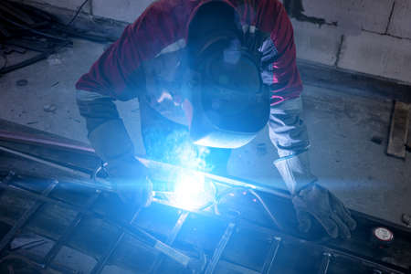 welder cooks metal and sparks fly close up