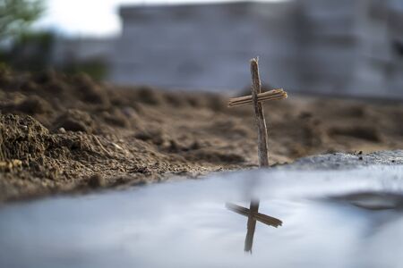 Christian cross made of wood on a background of sandの写真素材