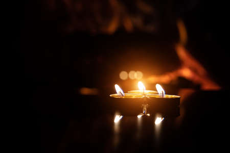 three candles on a black background with a fireplace flame.の写真素材
