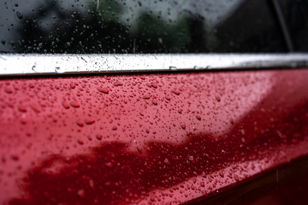 raindrops close up on a red car body macro photo.の写真素材