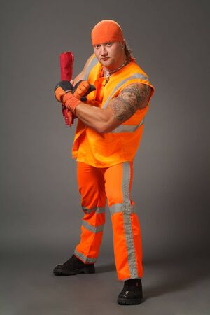 The worker in orange clothes on a grey background in studioの写真素材