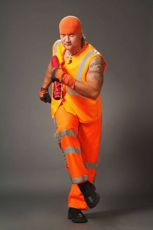 The worker in orange clothes on a grey background in studioの写真素材