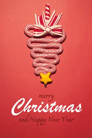 Christmas tree lollipop on a red background, Christmas tree upside down, merry Christmas text, unusual design for a postcardの写真素材