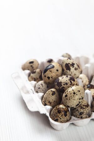 Easter quail eggs in container on bright backgroundの写真素材