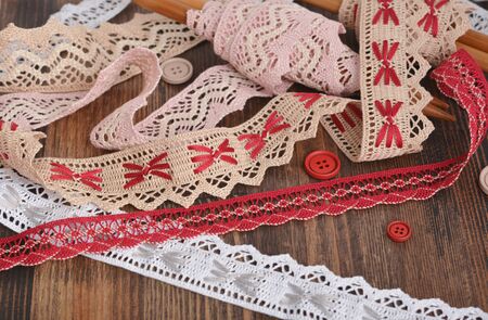 Pile of vintage cotton tapes and round buttons on wood background