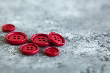 Pile of red matte buttons on concrete background, macro bokeh. beautiful needleworkの写真素材