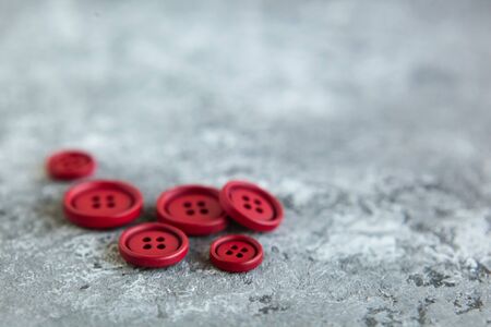Pile of red matte buttons on concrete background, macro bokeh. beautiful needleworkの写真素材