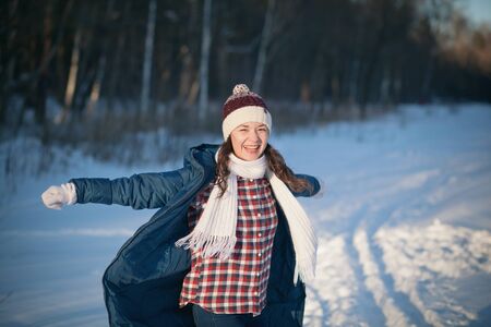 the beautiful young girl in a warm cap from wool of the alpaca in the winter forestの写真素材