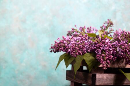 Purple lilac flowers bouquet on wooden box on black concrete background. Stylish floral greeting card. Happy mothers day.の写真素材