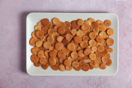 Trendy homemade breakfast, pancake cereal, mini pancakes on light plate on pink concrete background