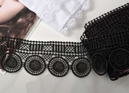 Tapes of black gentle guipure, beauty lace fabric on light background. Elastic material. Using for...