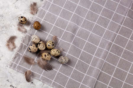 pile of Easter quail eggs on gray fabric rag on white concrete background. space for textの写真素材